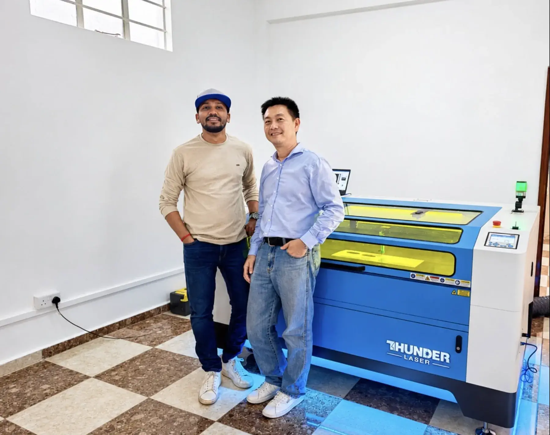 A Mauritian client and an Intergraph team member beside a newly installed Thunder Laser CO₂ machine