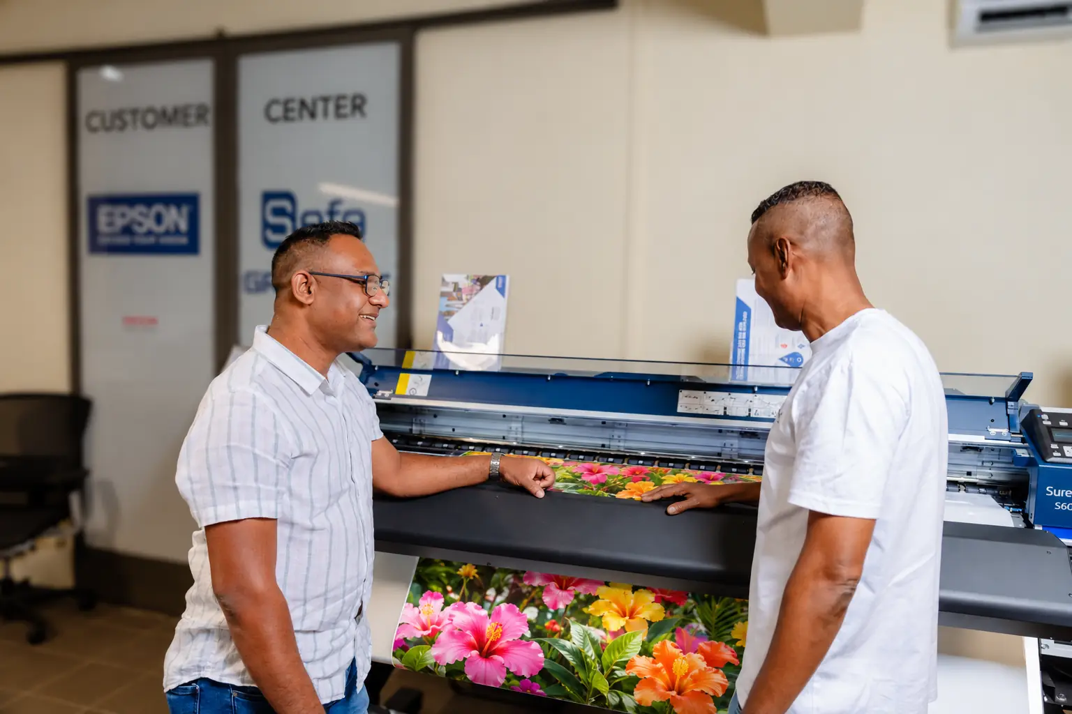 Customers looking at a tropical flower print on an Epson SureColor printer in the Intergraph showroom, Pailles